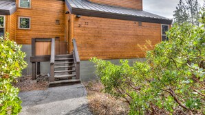 A two-story wooden cabin with a metal roof, a wooden staircase leading to a door, and a number '22' on the side.