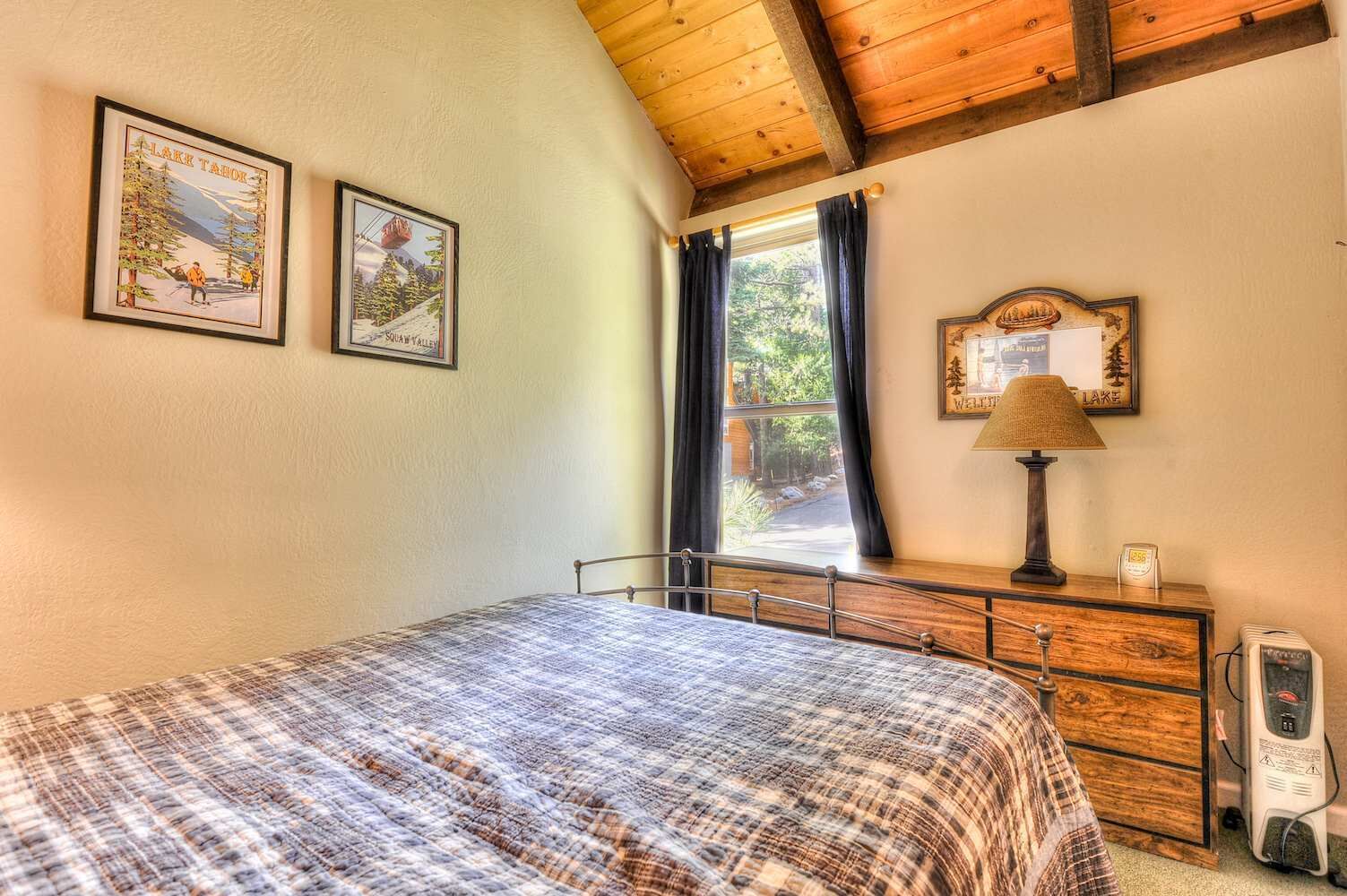 Une chambre à coucher avec un lit, une table de chevet, une lampe, une horloge et deux tableaux encadrés accrochés au mur.
