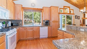 Una cocina con armarios de madera, encimeras de granito, lavavajillas y estufa.