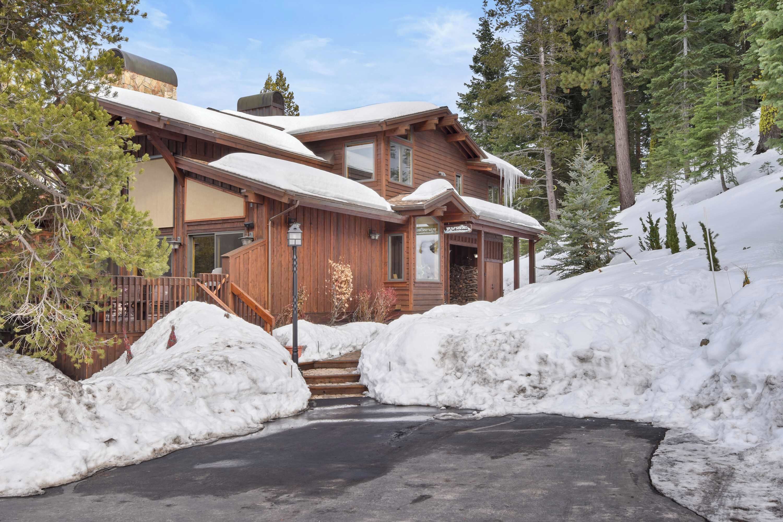 A wooden lodge with a covered porch and a snow-covered driveway.