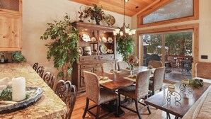 A spacious dining area with a wooden table and chairs, surrounded by a wooden cabinet with decorative items.