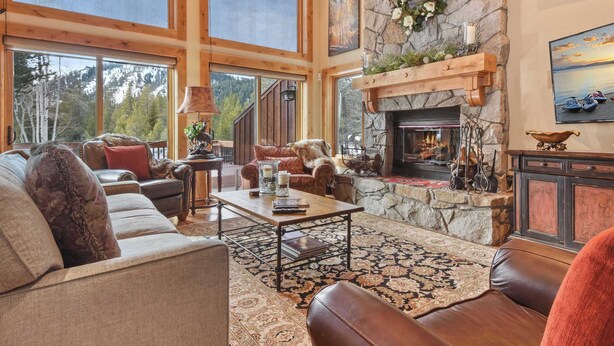 A spacious living room with a stone fireplace, large windows, and a cozy seating area.
