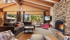 A cozy living room with a fireplace, a sofa, a coffee table, and a television. - Waters Edge Oasis | Shared Pool & Pier Access (Tahoma)
