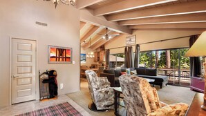 A spacious living area with a high ceiling, a fireplace, and a view of the outdoors. There are multiple seating options including a sofa and chairs. - Waters Edge Oasis | Shared Pool & Pier Access (Tahoma)