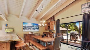 A wooden dining area with a large table, benches, and a chandelier. - Waters Edge Oasis | Shared Pool & Pier Access (Tahoma)