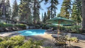 A pool area with lounge chairs and umbrellas, surrounded by tall trees. - Waters Edge Oasis | Shared Pool & Pier Access (Tahoma)