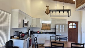 A modern kitchen with white cabinets, a wooden ceiling, and a deer head mounted on the wall. - Home Sweet Home (Sevierville)