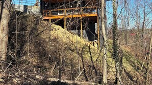 A multi-story wooden building with a balcony, surrounded by trees and a hillside. - Home Sweet Home (Sevierville)