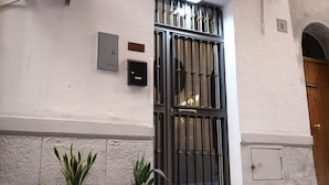 A building facade with a metal gate, potted plants, and a wooden door. - Cozy apartment in the heart of Palermo, Capo district, pets allowed (Palermo)