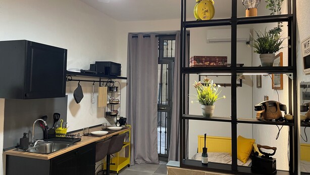 A compact kitchen with a sink, microwave, and a small dining area with chairs and a table. - Cozy apartment in the heart of Palermo, Capo district, pets allowed (Palermo)