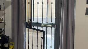A room with a metal gate door, a coffee machine, and a yellow shelf. - Cozy apartment in the heart of Palermo, Capo district, pets allowed (Palermo)
