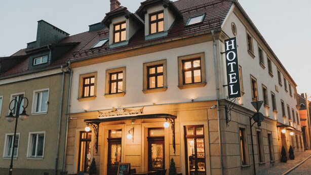 A hotel with a classic European architectural style, featuring a prominent entrance with a canopy and seating area outside. - HG Hotel Restauracja (Toszek)