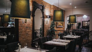 A restaurant with brick walls, dark wooden tables, and hanging lamps. - HG Hotel Restauracja (Toszek)
