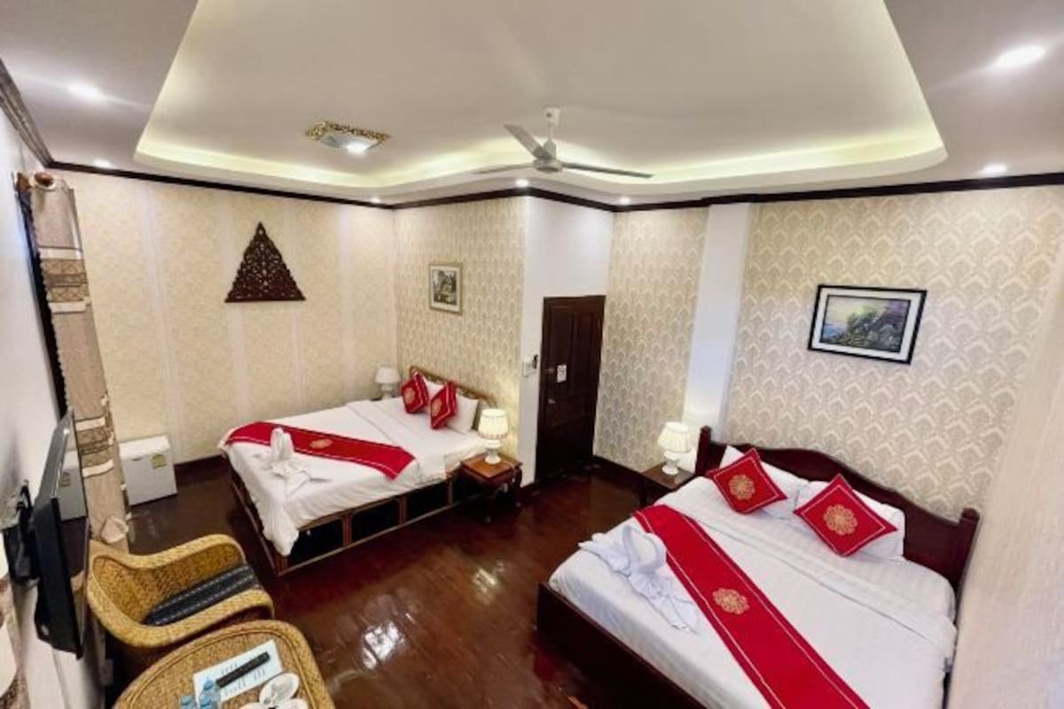 A hotel room with two beds, a ceiling fan, and a door.