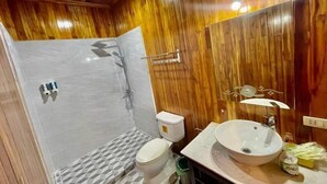 A bathroom with a shower, toilet, and sink, wooden walls, and a mirror.