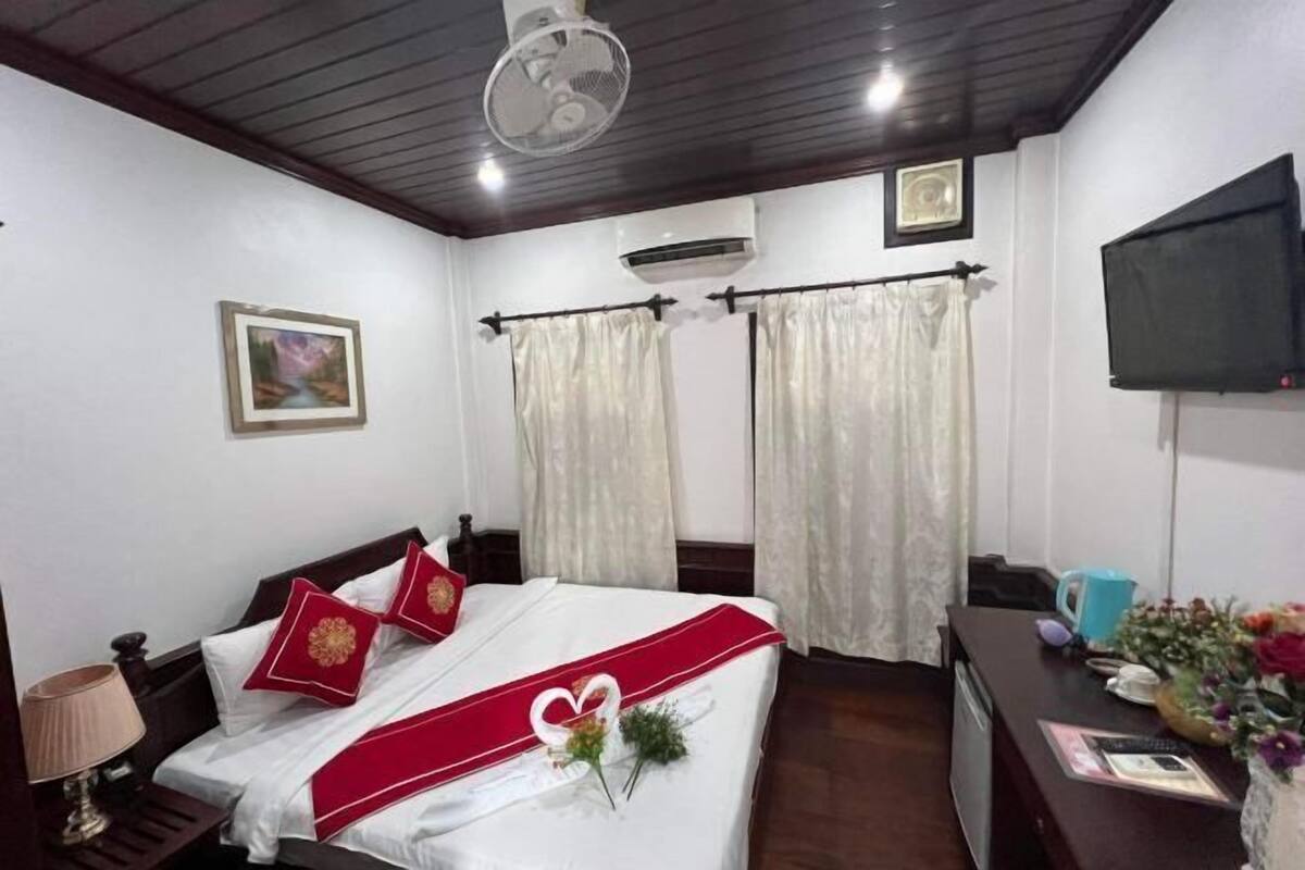 A hotel room with a bed, a desk, a TV, and curtains.
