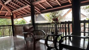 A covered outdoor seating area with wooden furniture and a railing.