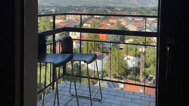 A balcony with two chairs and a view of a cityscape and mountains. - Lofts with breathtaking views (Gorizia)