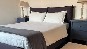 A neatly made bed with a grey and white duvet, two bedside tables with lamps, a dark wooden floor, and a beige rug. - Lofts with breathtaking views (Gorizia)