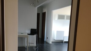 A spacious room with dark wooden flooring, a white desk, and a black chair. - Lofts with breathtaking views (Gorizia)
