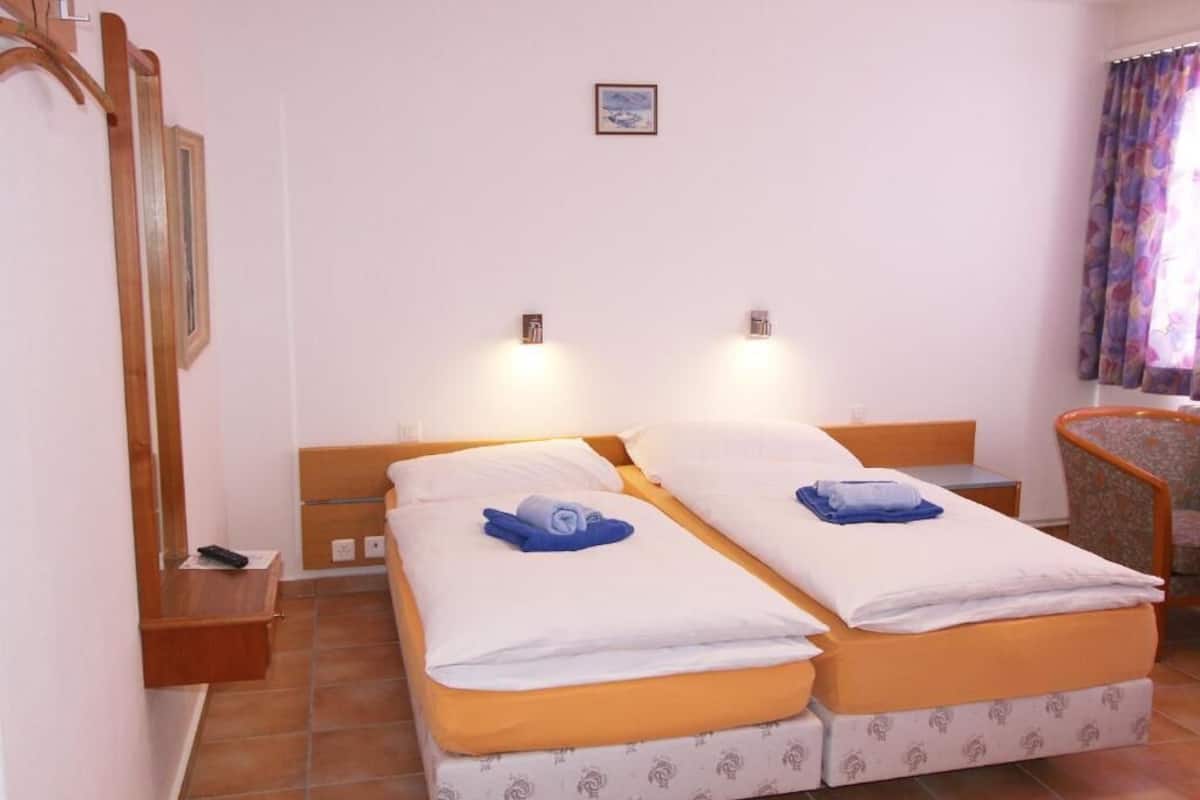 A double bed room with two bedside tables, a small desk, and a chair.