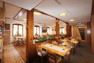 Un restaurante con mobiliario de madera, una barra central y amplios ventanales que dejan entrar la luz natural.