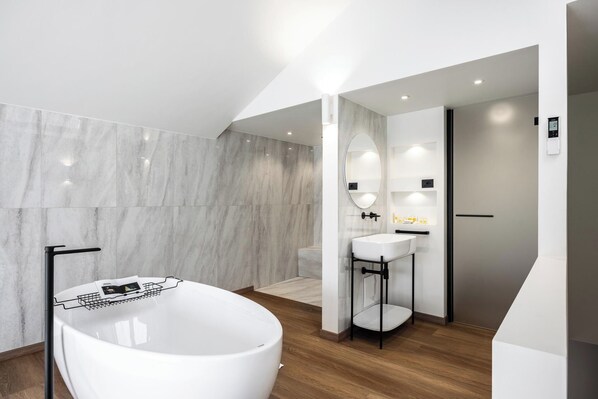 A modern bathroom with a freestanding bathtub, a vanity with a mirror, and a shower area.