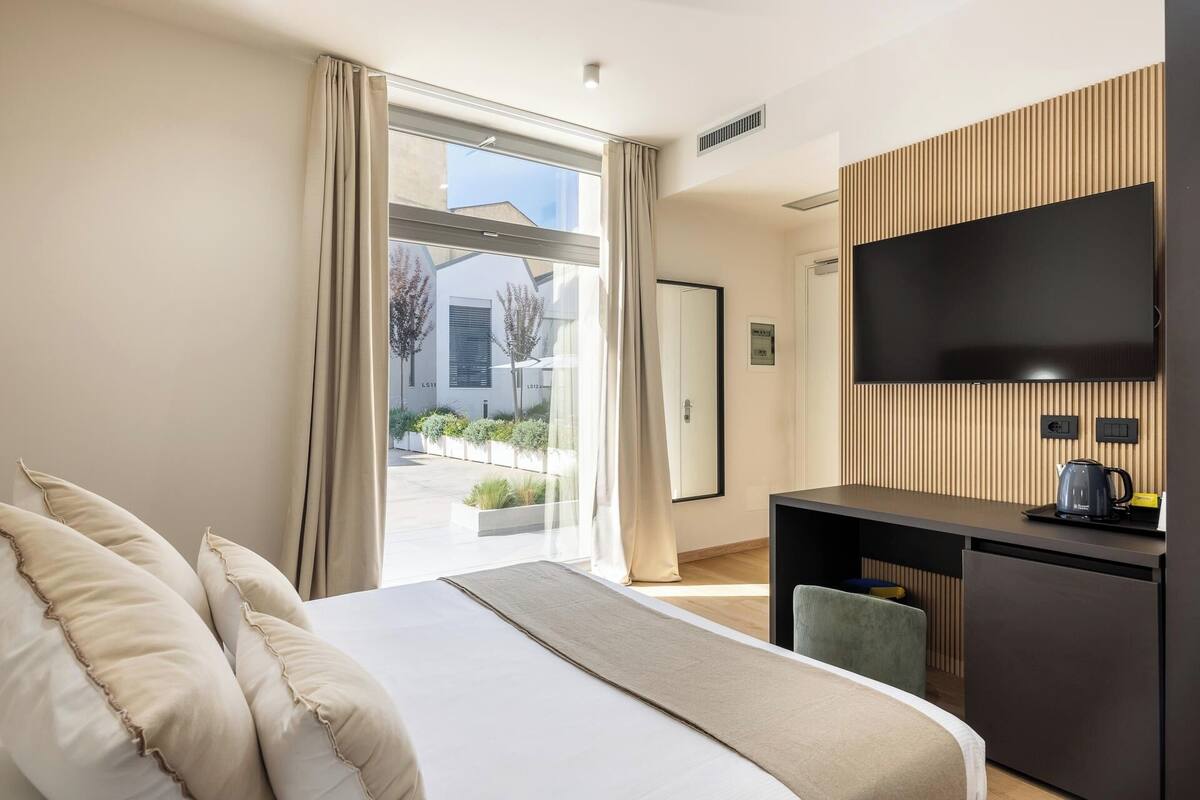 Une chambre d’hôtel moderne dotée d’un grand lit, d’une télévision à écran plat, d’un bureau et offrant une vue sur l’extérieur.