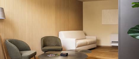 A modern living room with a round coffee table, two armchairs, a sofa, and a wall-mounted air conditioning unit.