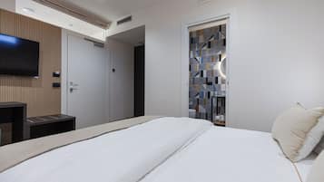 Ein modernes Hotelzimmer mit einem großen Bett, einem flachbildfernseher an der Wand, einer Wandverkleidung aus Holz und einer Tür mit einem geometrischen Fliesendesign.