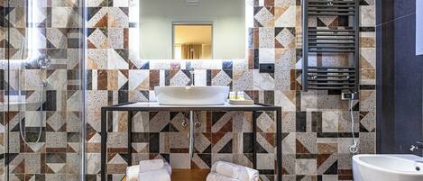 A modern bathroom with a geometric tile backsplash, a wooden vanity with a sink, and a large mirror.