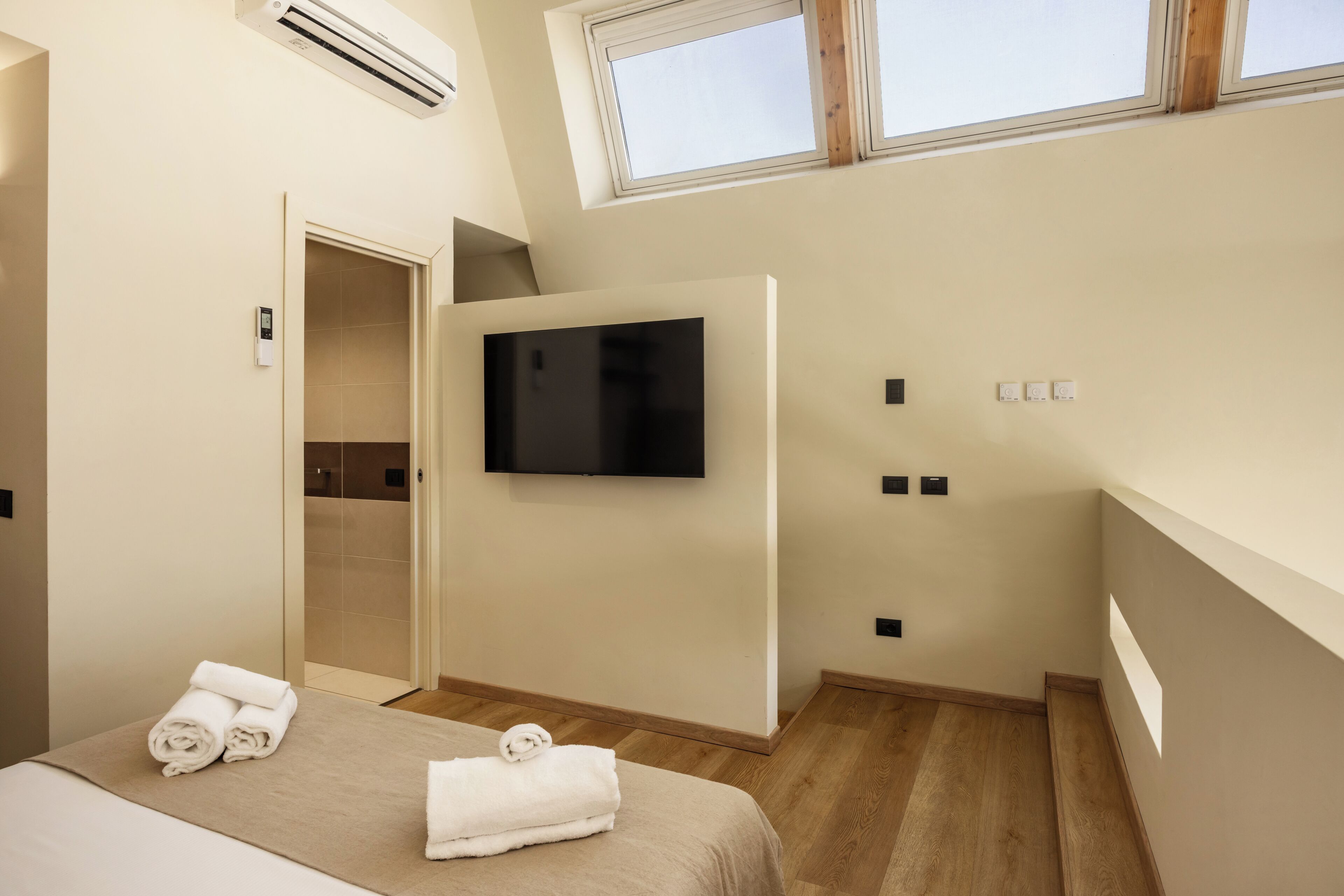 A modern hotel room with a bed, a flat-screen TV, a shower, and a window.