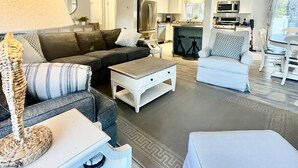 A modern living room with a sofa, coffee table, and a dining area with chairs and a table. - 6 Richards Way (Sandwich)