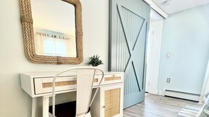 A room with a white desk, a mirror with a rope frame, a blue door, and a patterned rug. - 6 Richards Way (Sandwich)