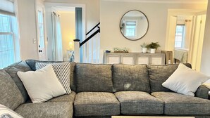 A living room with a sectional sofa, a white coffee table, and a staircase leading to another room. - 6 Richards Way (Sandwich)