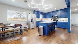 A modern kitchen with blue cabinets, a stainless steel refrigerator, a microwave, and a large island with stools. - 12 Minutes from Crossbar and Turner Falls, Sleeps up to 10, Fast Wi-Fi (Davis)
