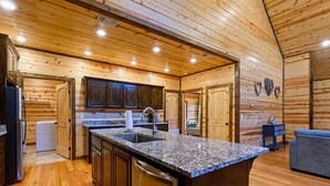 A modern kitchen with wooden walls, granite countertops, and built-in cabinetry.