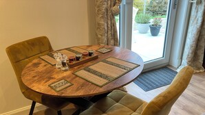 A round wooden dining table with four chairs, a set of condiment containers, and a doormat. - Pet-friendly luxury garden apartment surrounded by woodland and fields. (Clashmore)