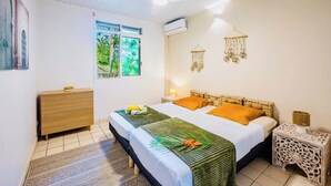 A bedroom with a bed, bedside tables, a window, and a wall-mounted air conditioner.
