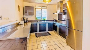 A modern kitchen with stainless steel appliances, a large window, and a view of the outdoors.