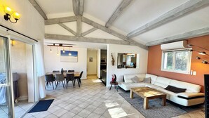 Ein geräumiges Wohnzimmer mit Esstisch, Sofas und einem großen Fenster.