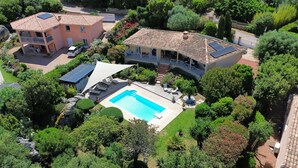 Ein Wohnhaus mit Swimmingpool, überdachter Terrasse und großem Garten.