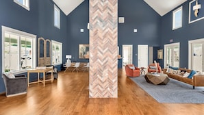 Un vaste salon doté d’un haut plafond, de grandes fenêtres et d’un pilier orné d’un motif en chevrons.