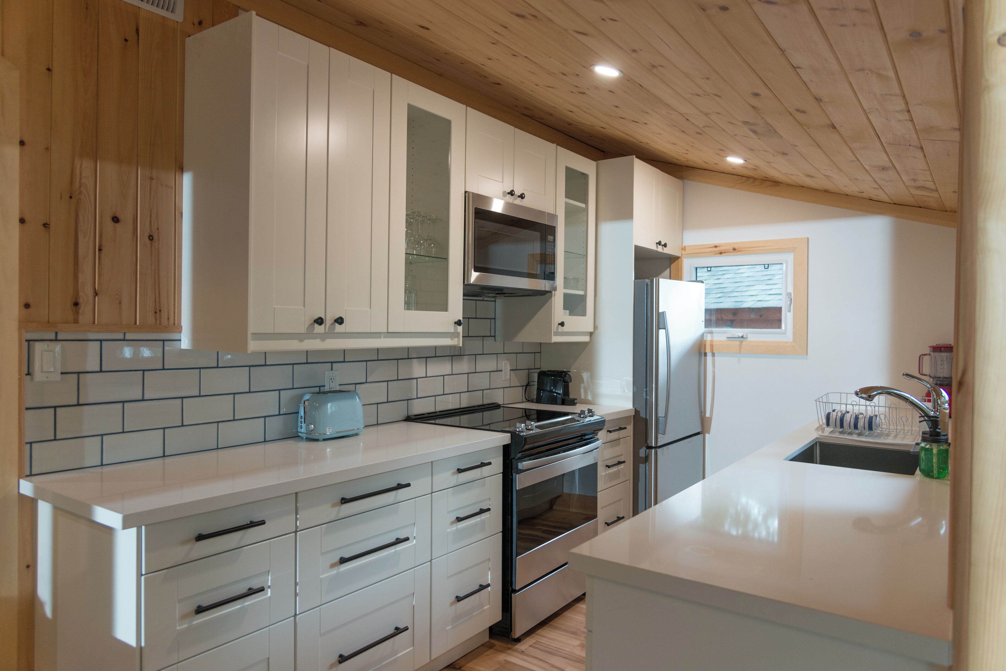 A modern kitchen with white cabinets, a stainless steel oven, and a built-in microwave.