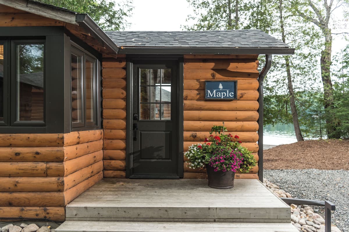 A log cabin with a black door and a sign that reads "Maple".