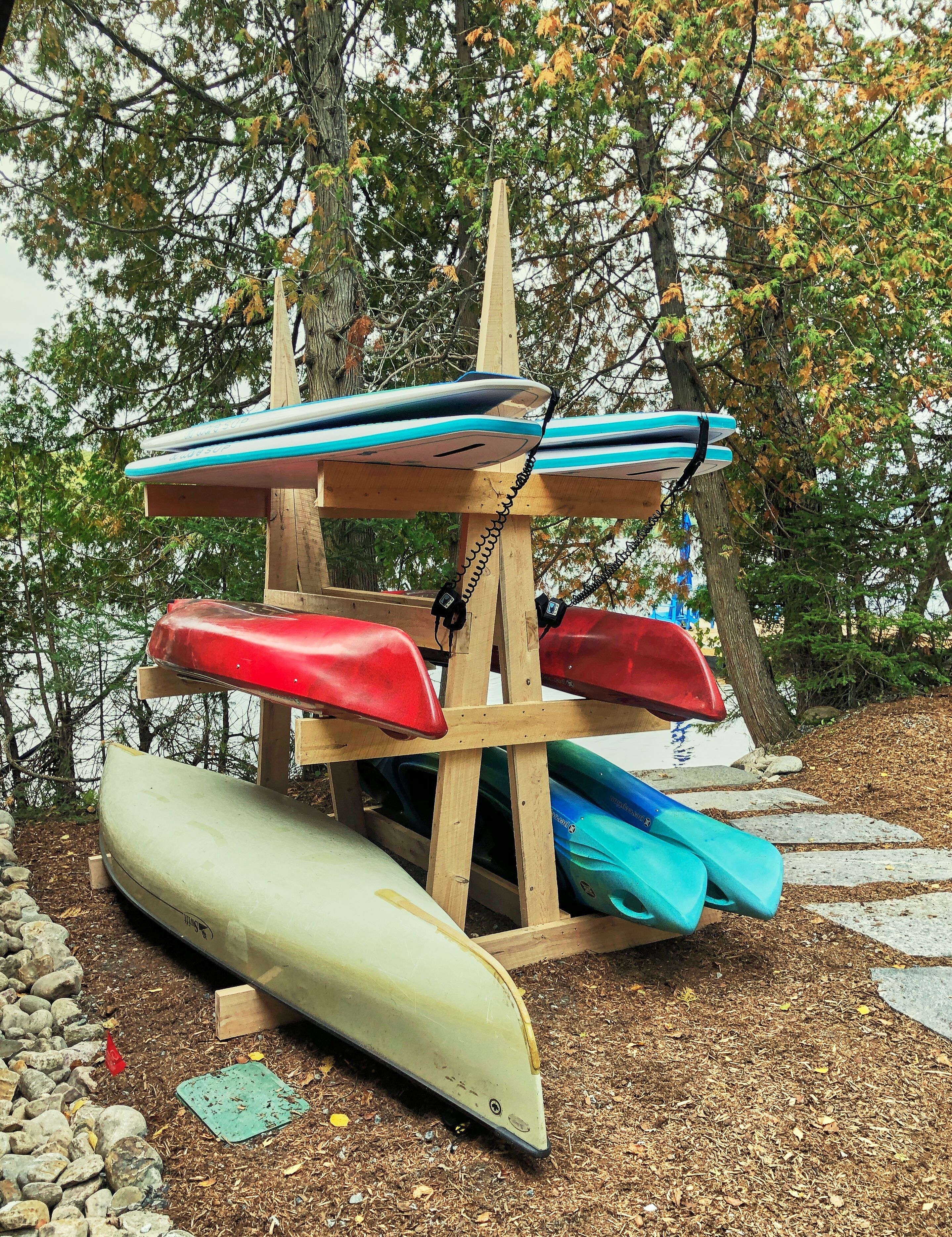 A wooden rack holding kayaks and a canoe.