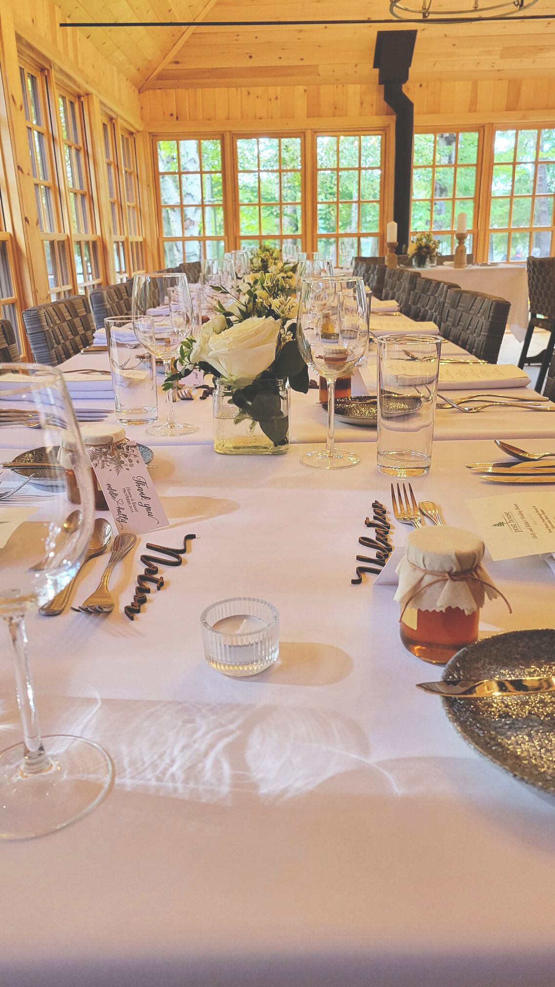 Une table à manger dressée pour un événement formel, avec de la verrerie, des couverts et un centre de table.