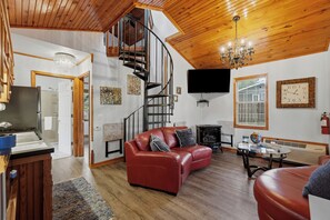 A modern living room with a red leather sofa, a fireplace, a flat-screen TV, and a wooden ceiling. - Stunning 2 Bedroom Cabin In The Woods, Covered Porch, Jacuzzi, Kitchen & Hot Tub (Eureka Springs)