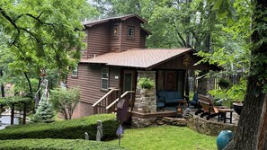 A rustic cabin with a stone foundation, wooden deck, and a porch with seating. - Stunning 2 Bedroom Cabin In The Woods, Covered Porch, Jacuzzi, Kitchen & Hot Tub (Eureka Springs)