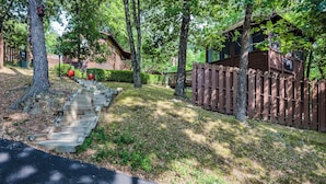 A wooden cabin with a wooden deck and a staircase leading to a porch. - 1 Bedroom Cabin In The Woods, Covered Porch, Jacuzzi, Kitchen & Hot Tub. (Eureka Springs)
